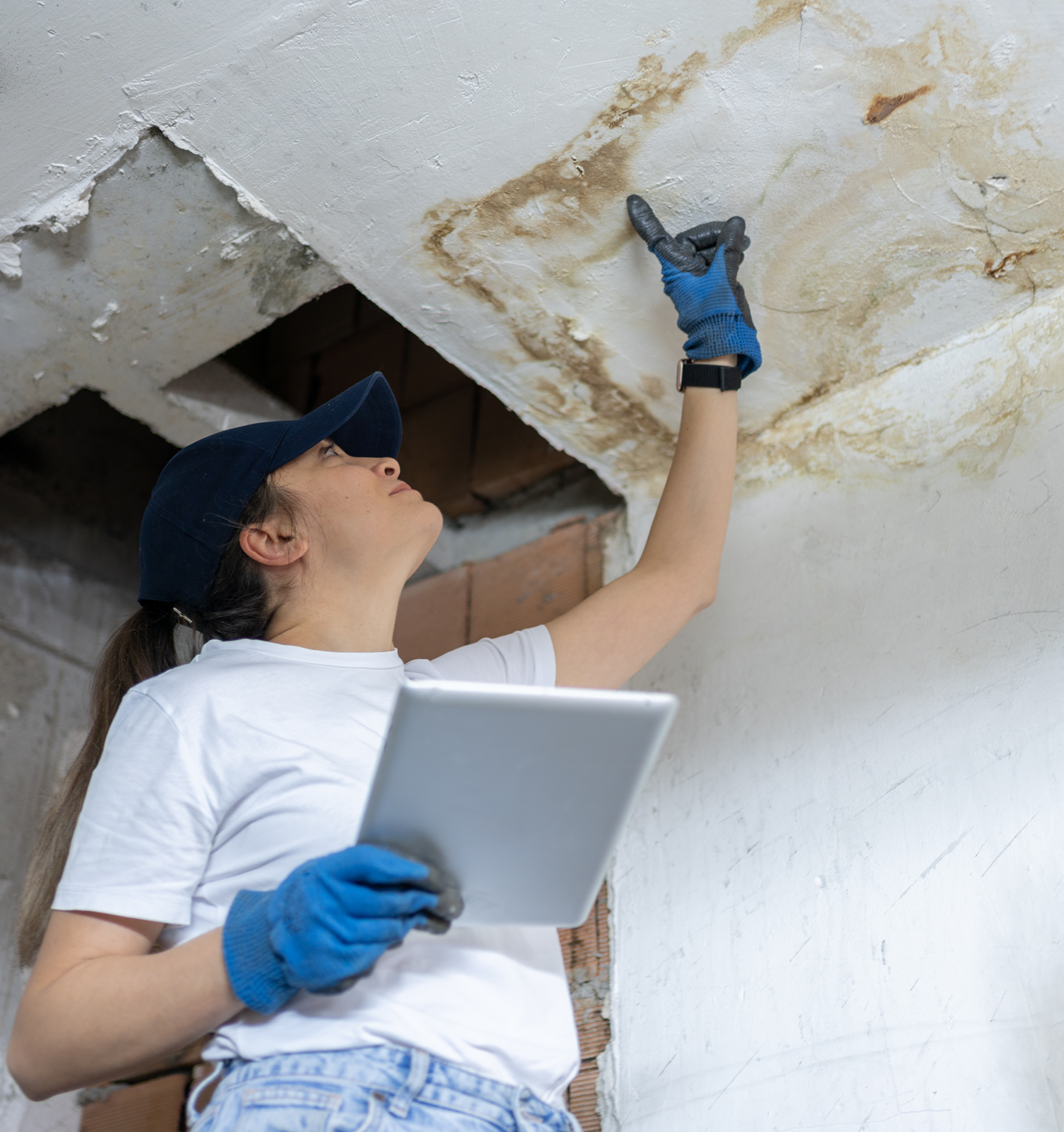 Worker inspecting ceiling water damage with tablet