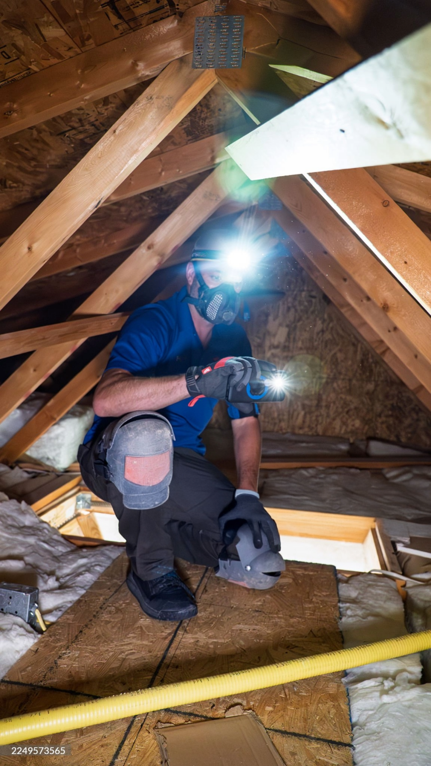 Worker inspecting attic with headlamp and flashlight