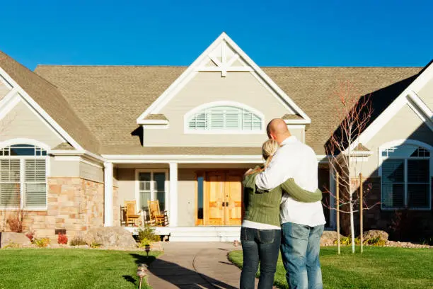 Couple embracing outside new suburban home